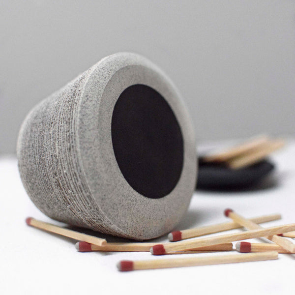 Handmade ceramic match striker in gray clay body with a ribbed texture and striker paper fixed to the bottom to light matches