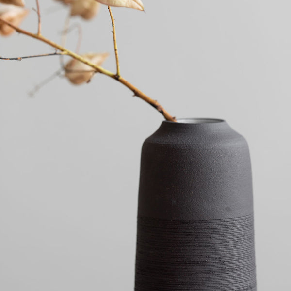 Handmade ceramic vase in black with a ribbed texture used for dried stems and floral arrangements