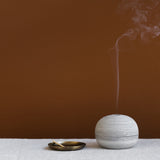 Ceramic incense holder burning an incense cone or smudge stick for meditation and mindfulness rituals